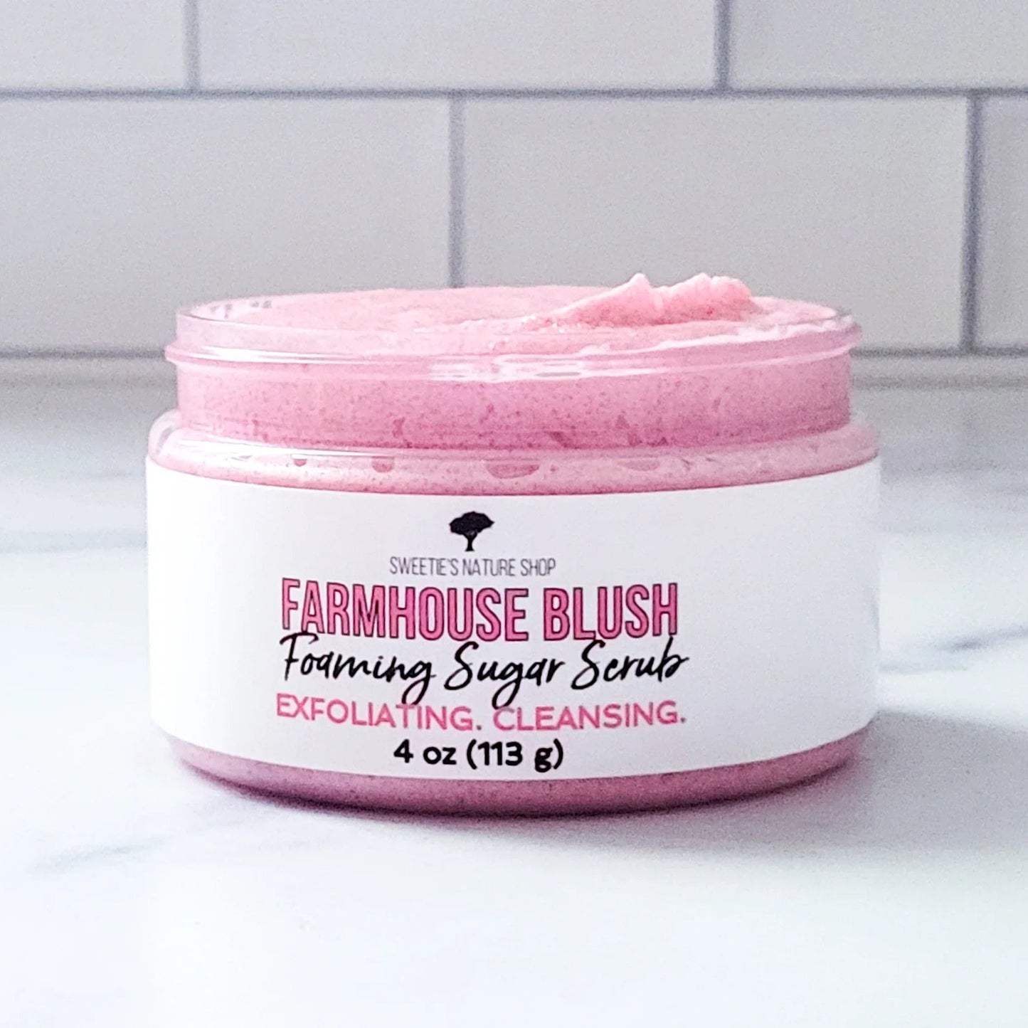 Jar of Farmhouse Blush foaming sugar scrub on a white surface with a tiled wall background