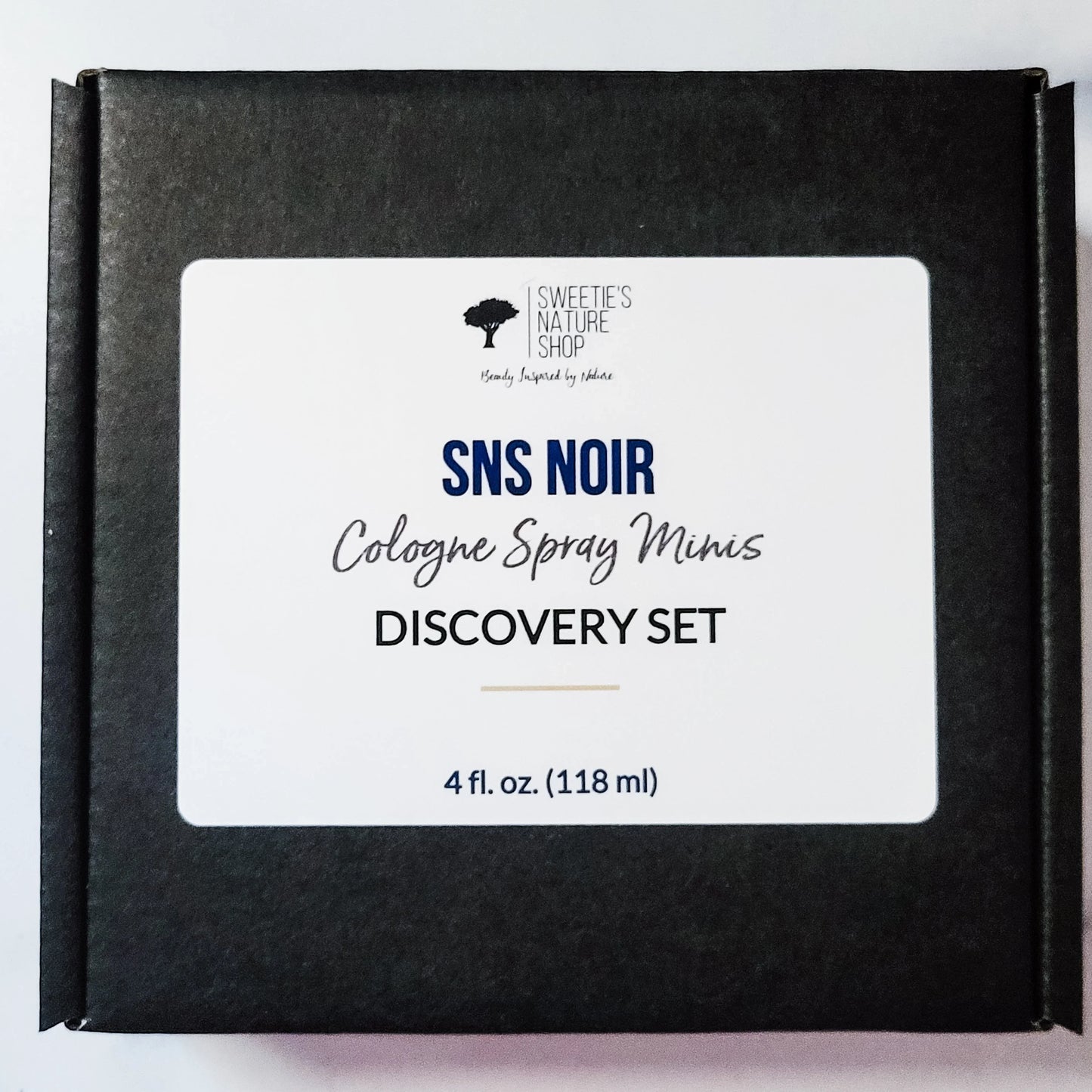 Black box with 'SNS Noir' cologne spray mini discovery set label on a light gray background