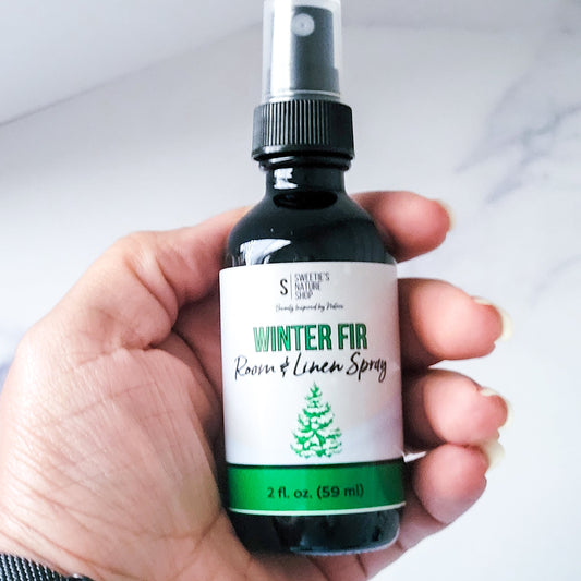 Hand holding a bottle of 'Winter Fir Room & Linen Spray