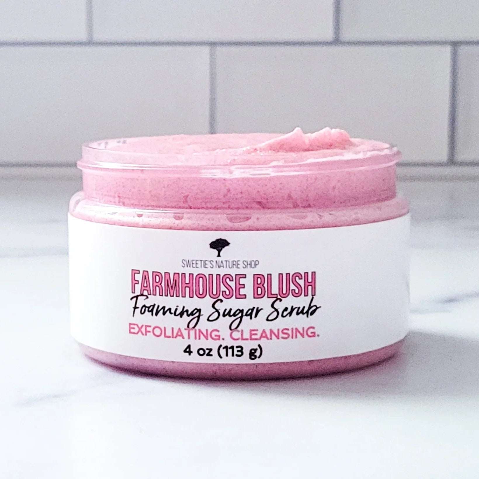 Jar of Farmhouse Blush foaming sugar scrub on a white surface with a tiled wall background