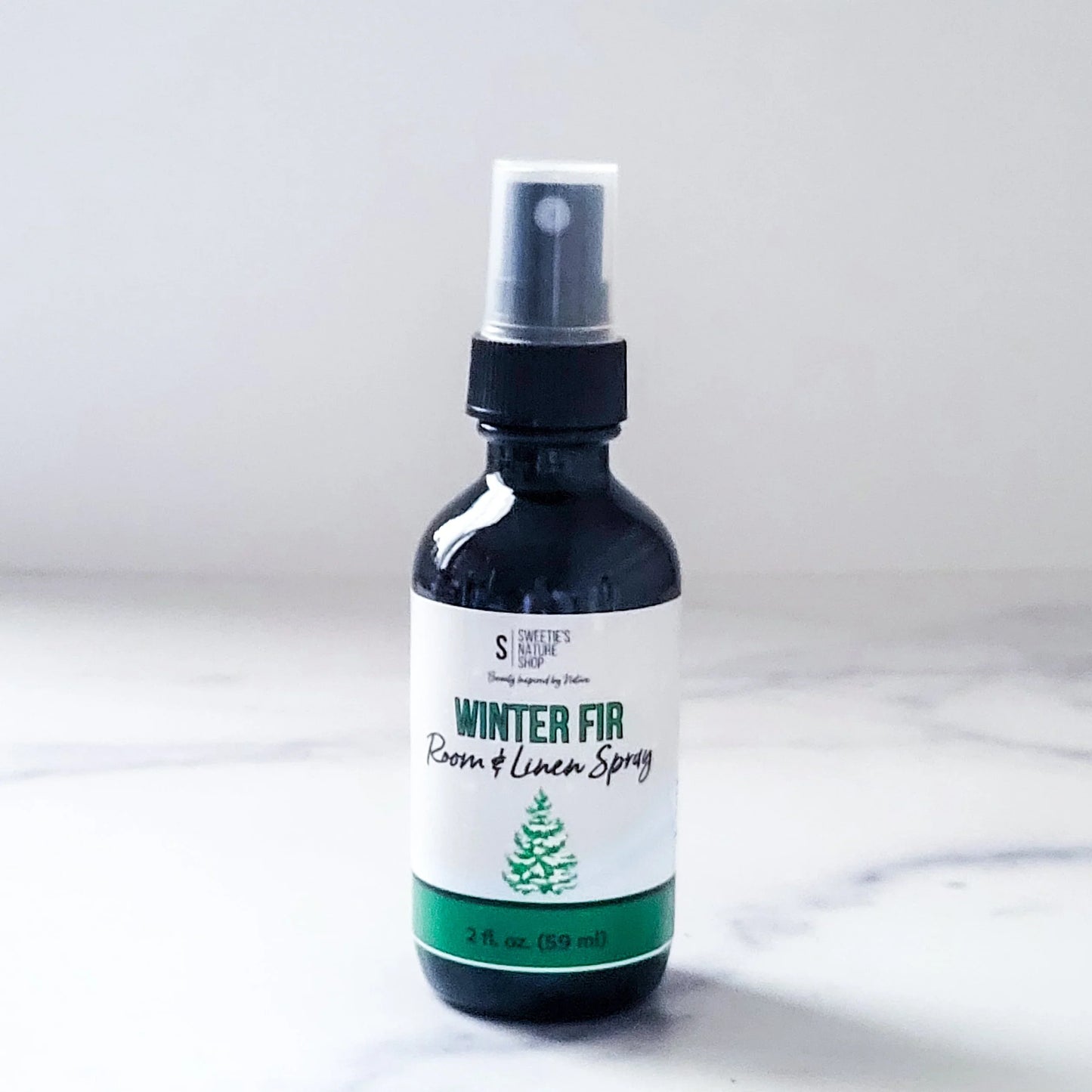 Bottle of 'Winter Fir' room and linen spray on a white background