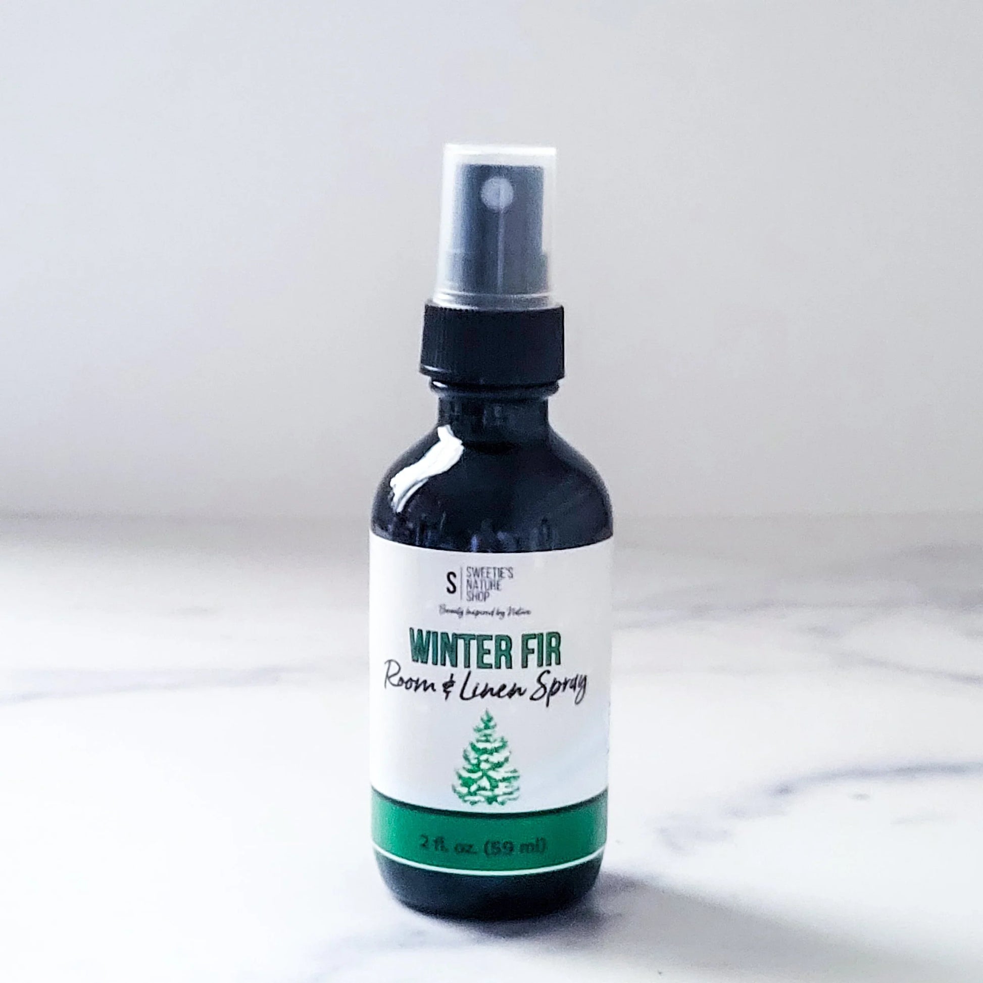 Bottle of 'Winter Fir' room and linen spray on a white background